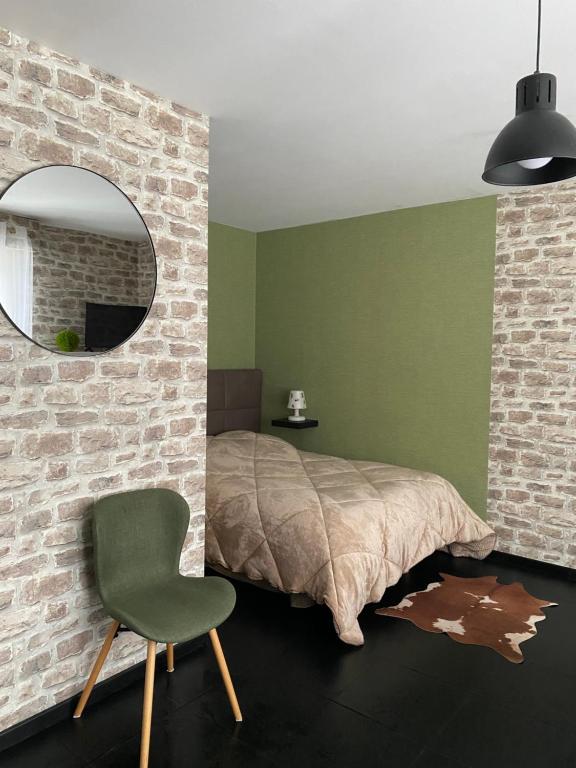 1 dormitorio con cama, silla y espejo en BUSINESS APPART HÔTEL MONTBÉLIARD, en Montbéliard