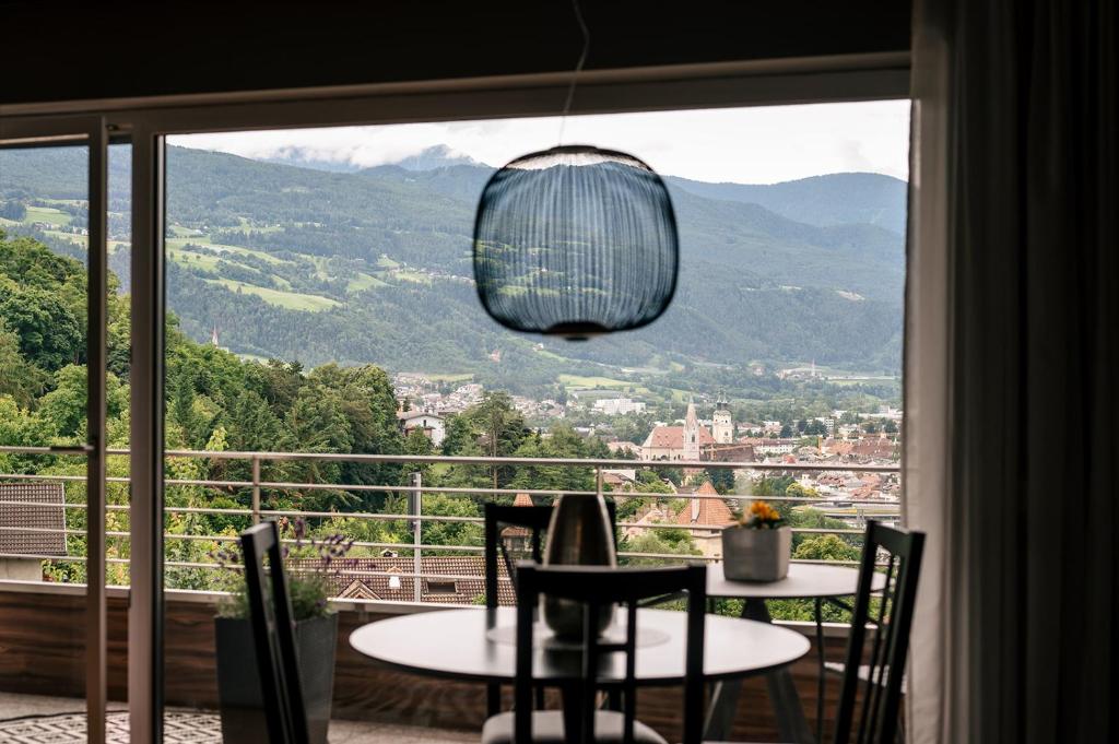 Una habitación con una mesa y sillas y una ventana grande. en Cityview Brixen, en Bresanona