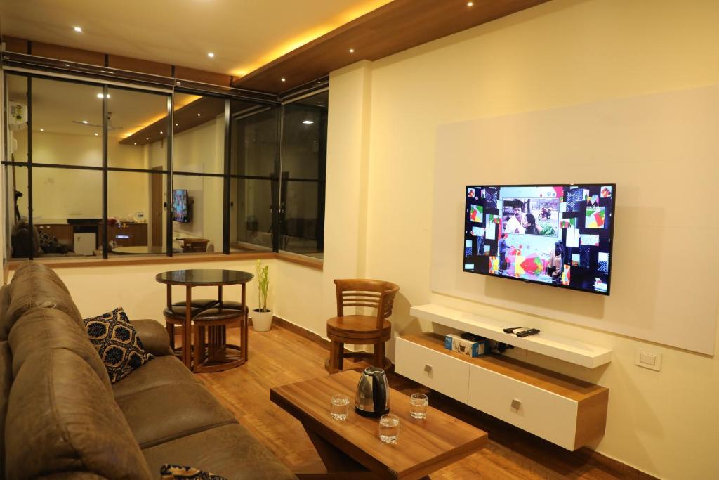 sala de estar con sofá y TV de pantalla plana en MEDLEY REGENCY, en Palakkad