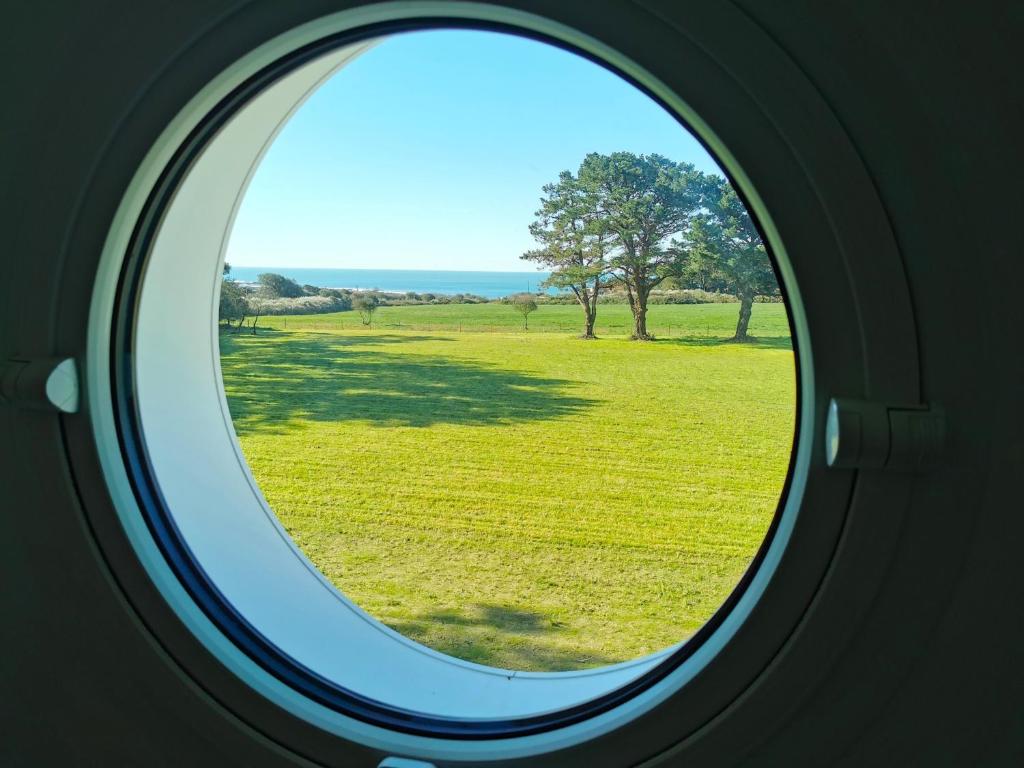 une fenêtre ovale donnant sur un champ d'herbe dans l'établissement Port Jure Face a la mer, à Les Sables-dʼOlonne