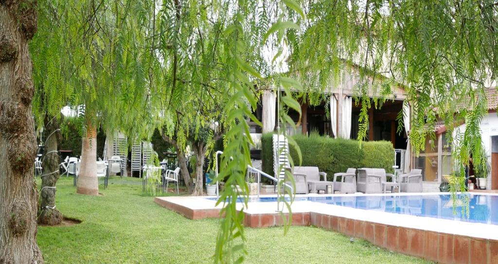 un complexe avec une piscine, des chaises et des arbres dans l'établissement Hostal Al-Andalus, à La Guijarrosa