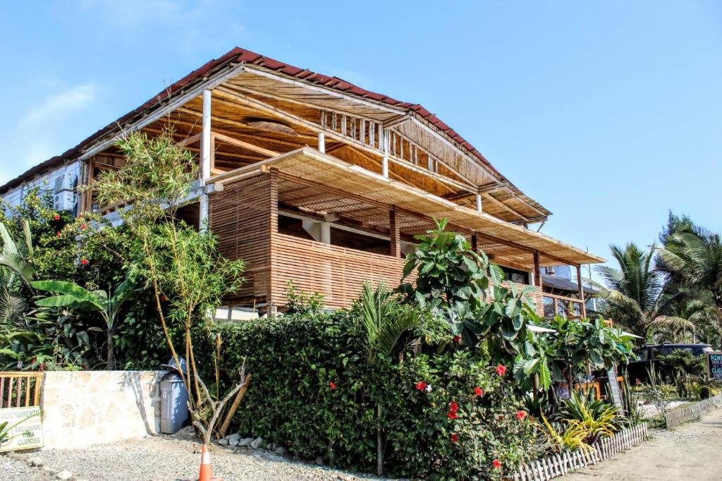 una casa con árboles y plantas delante de ella en Aloha.ayampe en Ayampe