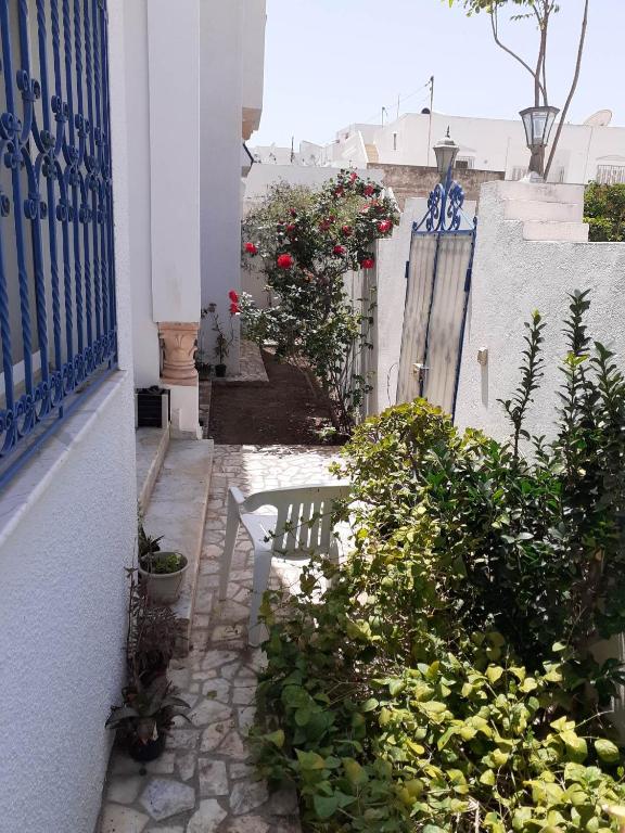 an alley with a bench and flowers and a fence at Villa S+3 Bien Equipée à 200m de la plage in Hammamet