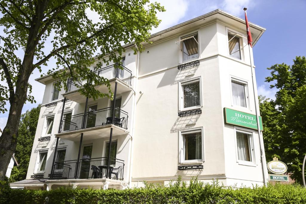 Biały budynek z zielonym znakiem przed nim w obiekcie Hotel Marienthal Garni w mieście Hamburg