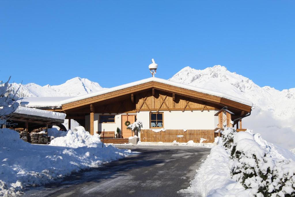 a building covered in snow with mountains in the background at Landhaus Eiter in Arzl im Pitztal