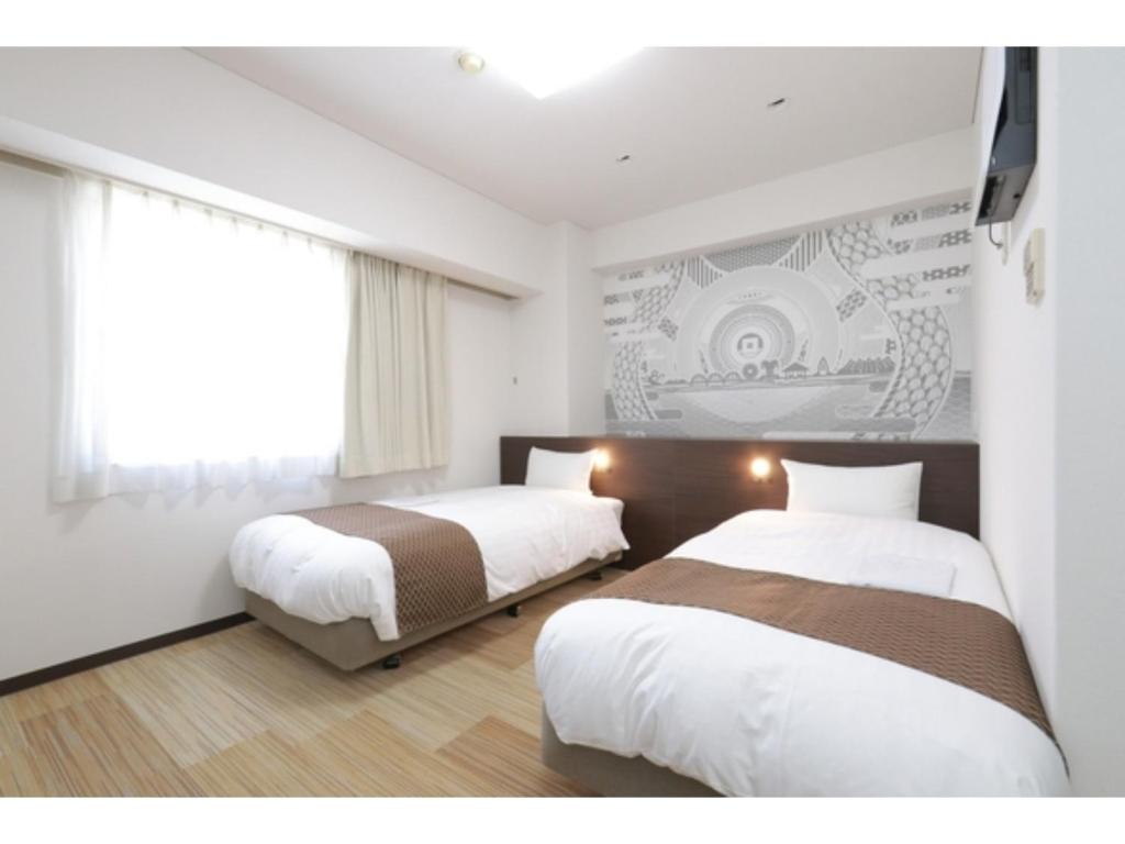 Hotel Sunny Inn - Vacation STAY 20470v في Kanonji: غرفة نوم بسريرين وتلفزيون على الحائط