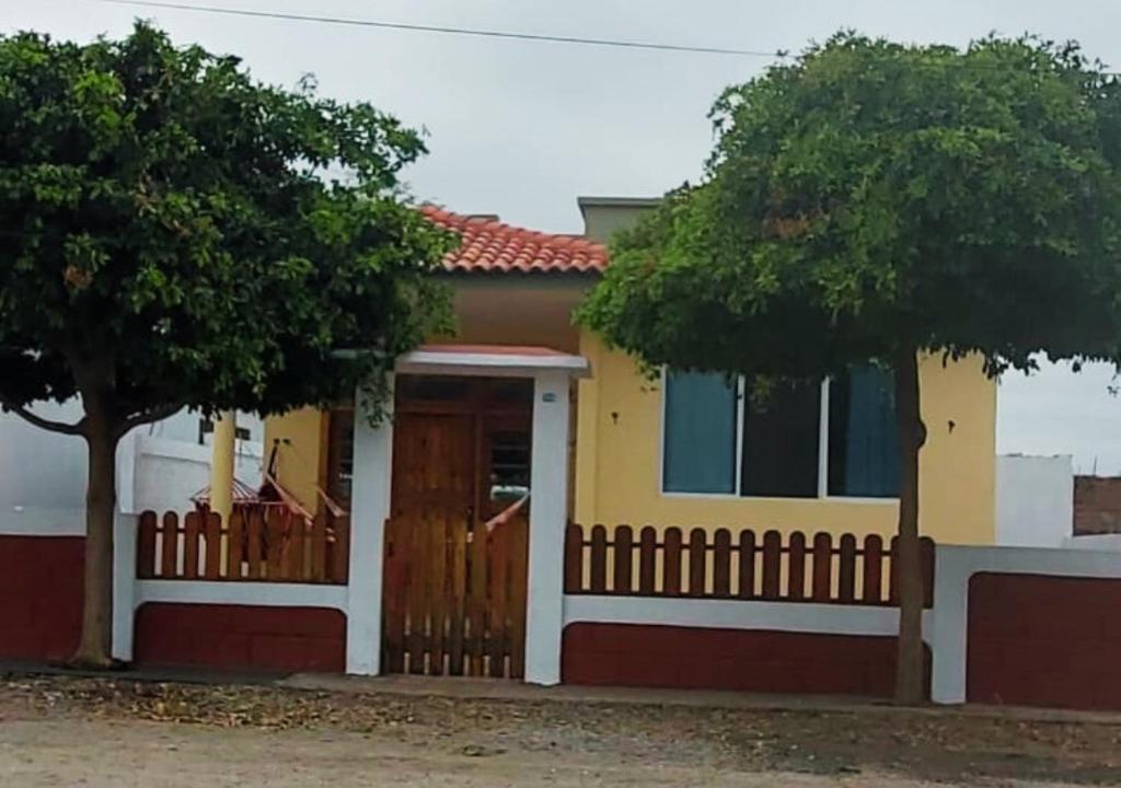 uma casa amarela e branca com uma cerca e uma árvore em Paraíso Costero en Alquiler em Playas