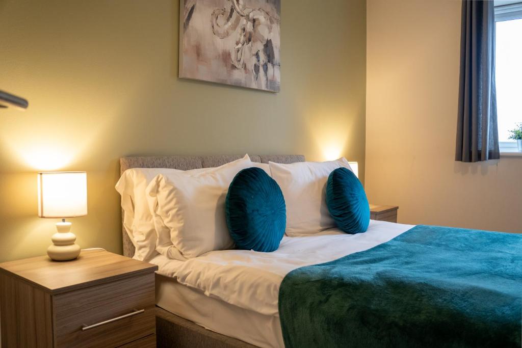 a bedroom with a bed with blue pillows at Modern Two Bedroom Apartment with Free Parking, Wifi & Sky TV by HP Accommodation in Milton Keynes