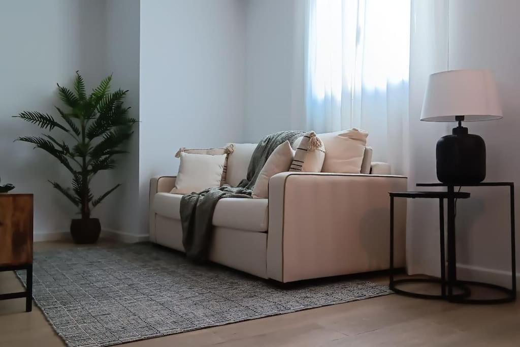 - un canapé blanc dans un salon avec une plante dans l'établissement Trotamundos, apartamento nuevo en el centro, à Cordoue