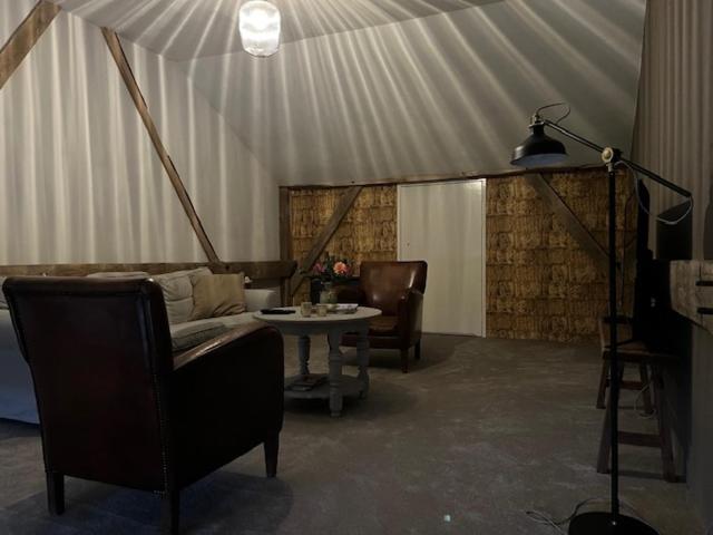 ein Wohnzimmer mit einem Sofa, Stühlen und einem Tisch in der Unterkunft De Citadel - De Boomgaard in Markelo