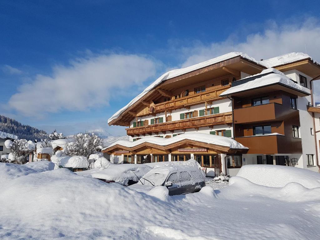ein schneebedecktes Gebäude mit viel Schnee drum herum in der Unterkunft Frühstückspension Tannenhof in Kirchberg in Tirol
