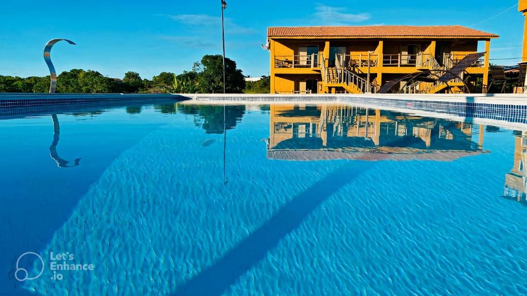 a swimming pool with a building in the background at Pousada Vila do Sol Corumbau in Corumbau
