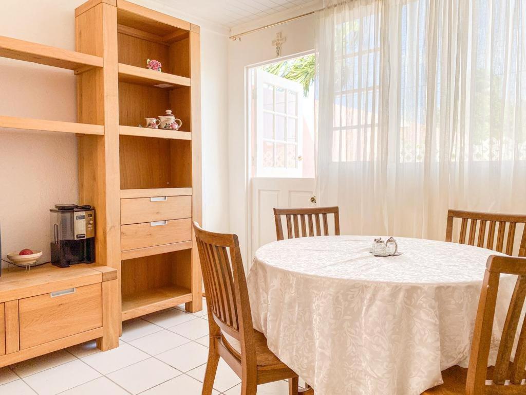 d'une salle à manger avec une table, des chaises et une fenêtre. dans l'établissement Tropical Retreat Stay Aruba, à Oranjestad