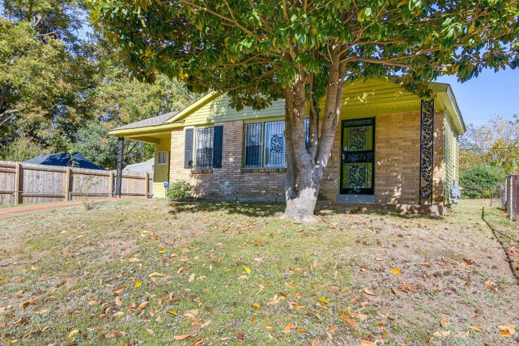 a small yellow house with a tree in the yard at Cozy Memphis Vacation Rental Near Beale Street! in Memphis