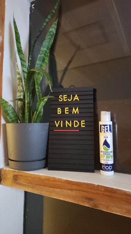 un livre noir assis sur une étagère avec une plante dans l'établissement Casa Ipê Baobá, à São Paulo