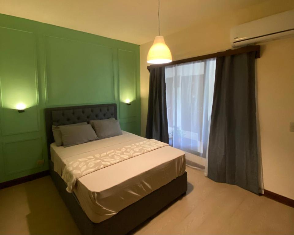 - une chambre verte avec un lit et une fenêtre dans l'établissement Oasis by Franklin Hotel Boutique, à Fortuna