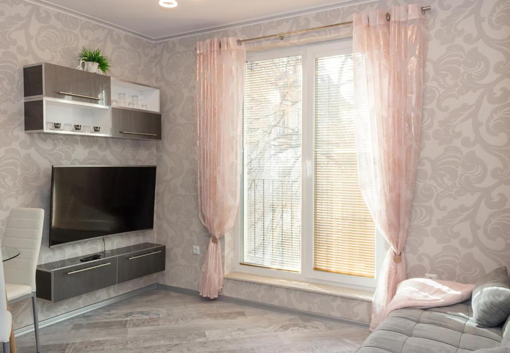 sala de estar con TV y ventana en Cozy Central Apartment, en Varna
