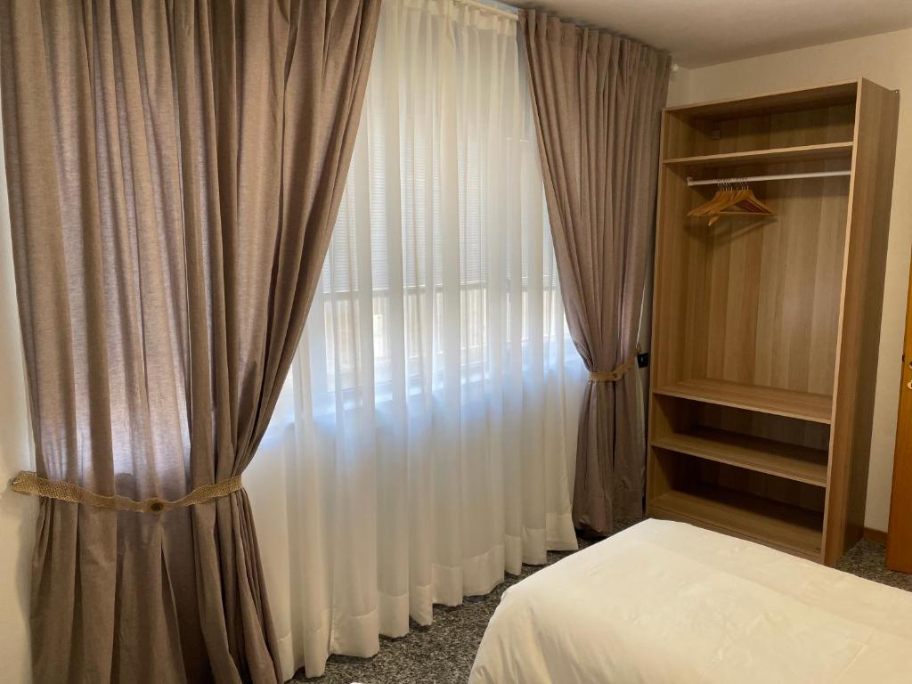 sypialnia z łóżkiem i oknem z zasłonami w obiekcie Melannie's Apartment w Bergamo