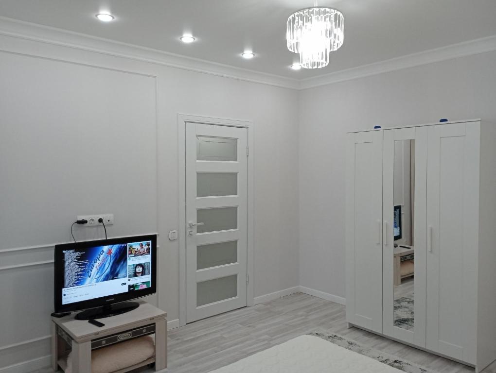 1-но комнатная квартира в центре Астаны ЖК Sezim Qala 4 في أستانا: غرفة بيضاء مع تلفزيون على طاولة