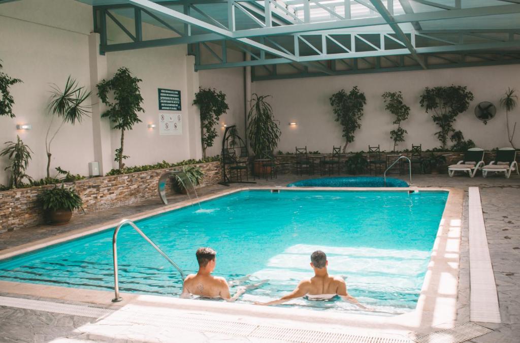 two men are sitting in a swimming pool at Casa Real Hotel in Salta