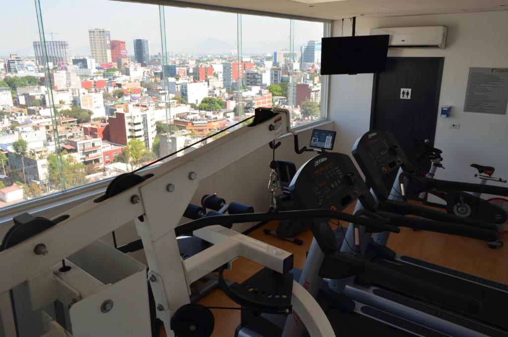 A compact fitness room with cardio and strength equipment overlooking Mexico City.