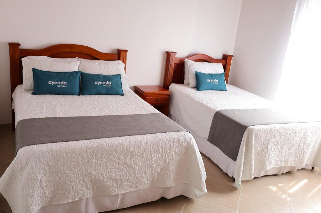 two beds with blue pillows in a room at Ayenda Torre 2 in Apartadó