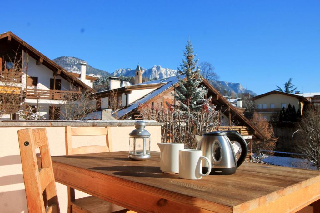 d'une table en bois avec des tasses et une lanterne sur le balcon. dans l'établissement CASA DOLOMIA - vista Dolomiti, Dolomiti Affitti, à Cavalese