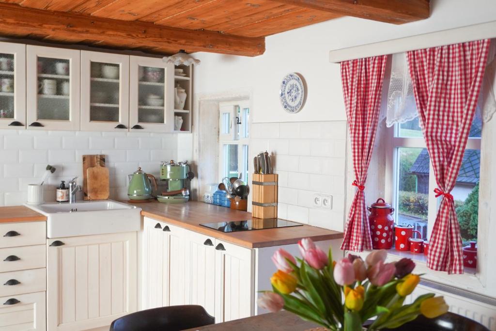 una cucina con armadi bianchi e un tavolo con fiori di Chalupa na Valech a Krompach