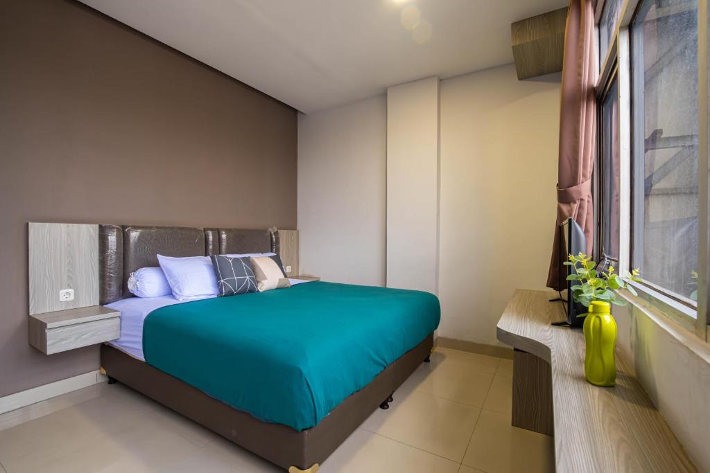 a bedroom with a blue bed and a window at Kelowna Mangga Besar by AbdiHome in Jakarta