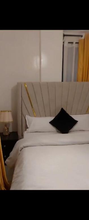 - une chambre avec un lit blanc et un oreiller noir dans l'établissement Triad apartments and Tsavo apartment, à Nairobi