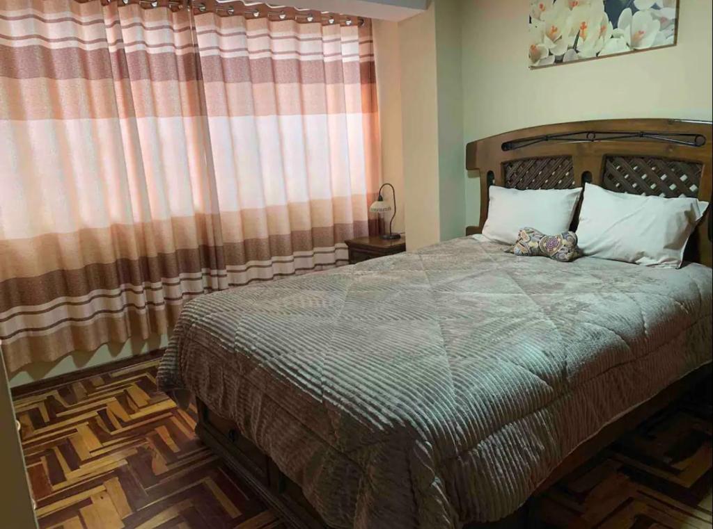 a bedroom with a bed and a window with curtains at Alojamiento a una cuadra de la plaza de armas in Puno