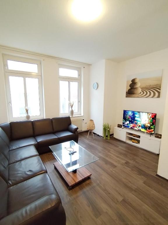 een woonkamer met een leren bank en een flatscreen-tv bij Schwert Ferienwohnung Monteurwohnung Verden in Verden