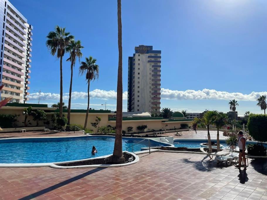 una piscina con palmeras y un edificio en Tenerifeopenhome Club Paraiso, en Adeje
