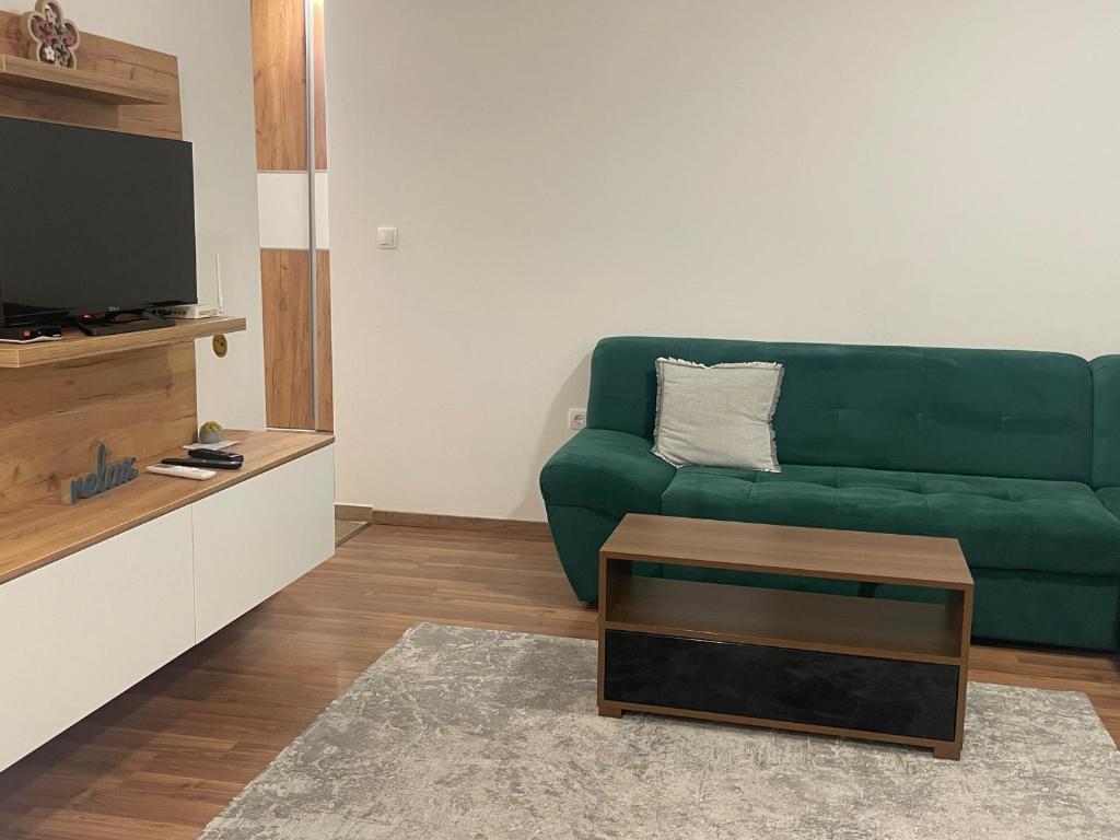 sala de estar con sofá verde y TV en Happy Apartment, en Prijedor