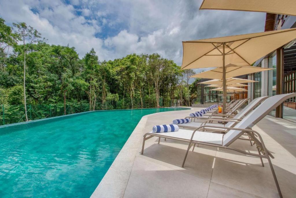 una piscina con sedie a sdraio e ombrelloni di Suite Quadruplo 7 dias - Wyndham Gramado Termas Resort & Spa a Gramado