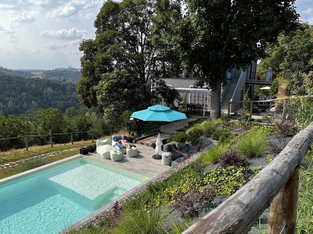 uma piscina com cadeiras e um guarda-sol ao lado de uma casa em Cascina GianTino G A Y - ONLY suite Cantina em Montegrosso dʼAsti