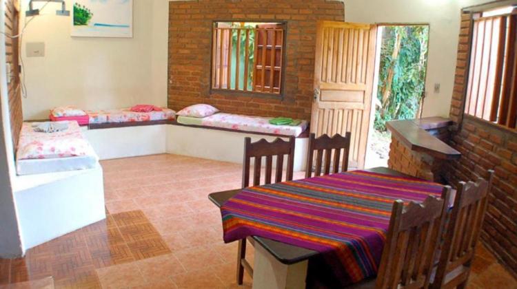 a room with a table and chairs and a room with beds at Pousada Lawrence in Itacaré