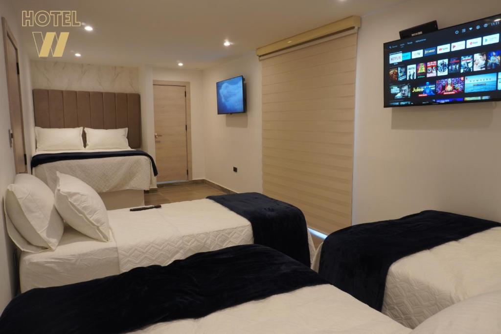a room with three beds and a tv on the wall at HOTEL W Santa Marta in Gaira
