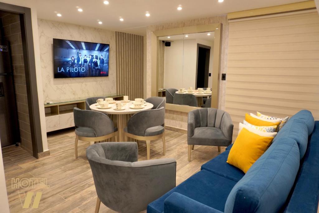 a living room with a blue couch and a table and chairs at HOTEL W Santa Marta in Santa Marta