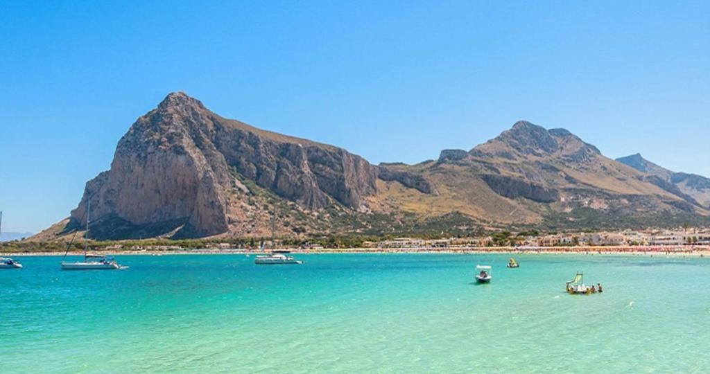 a beach with boats in the water with mountains in the background at Appartamento LG in San Vito lo Capo