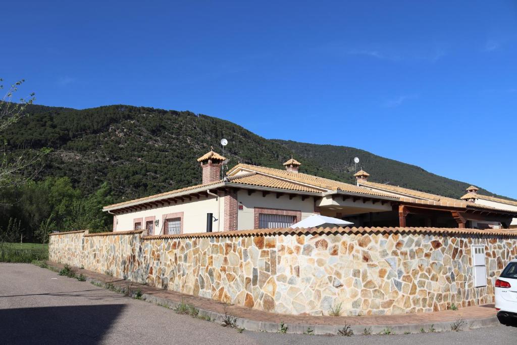 una casa detrás de una pared de piedra con una montaña en Casa en sierra de gredos piscina privada, en La Adrada