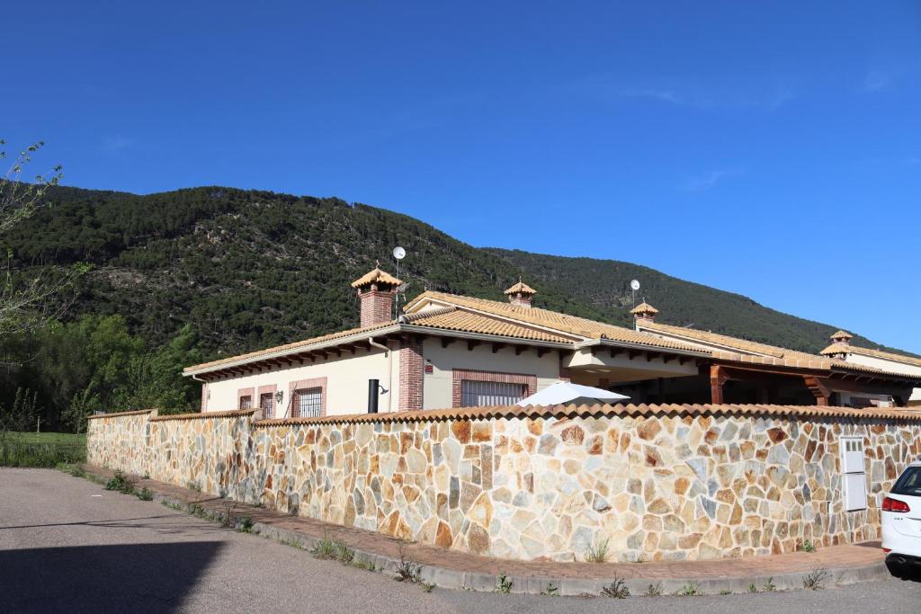 ein Haus hinter einer Steinmauer mit einem Berg in der Unterkunft Casa en sierra de gredos piscina privada in La Adrada