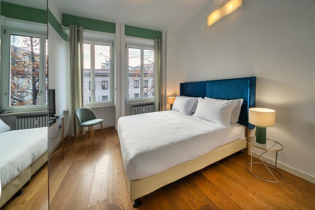 a bedroom with a bed and a desk and two windows at Santa Sofia Home in Milan