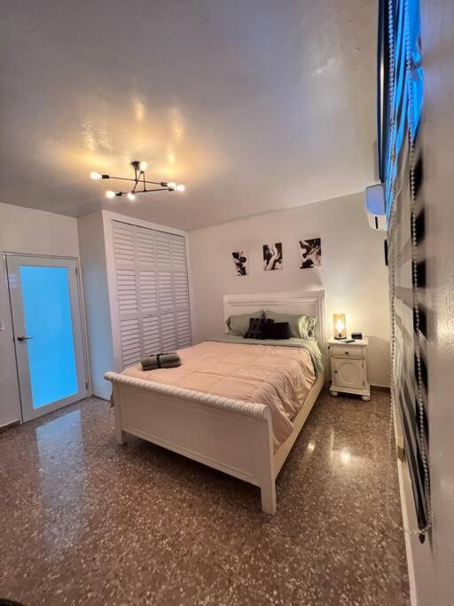 Playa y Campo Apartment #2 في إيزابيلا: غرفة نوم بسرير ابيض وموقف ليلي