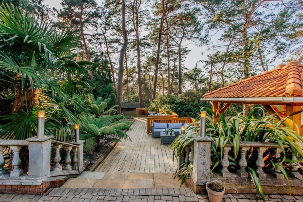 un jardín con una pasarela de madera con bancos y árboles en Hot Tub/Football Court/Sleeps 12/Luxury Villa en Parkstone