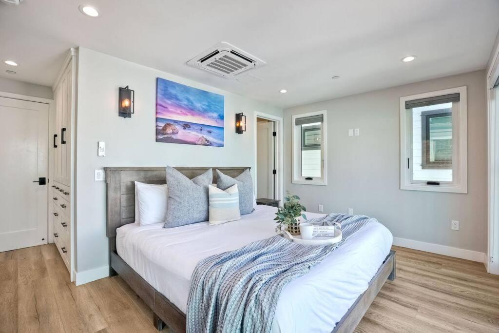 a bedroom with a large white bed with a table on it at NEW Luxury Beach Home I 3BR I Balcony I Firepit in San Diego