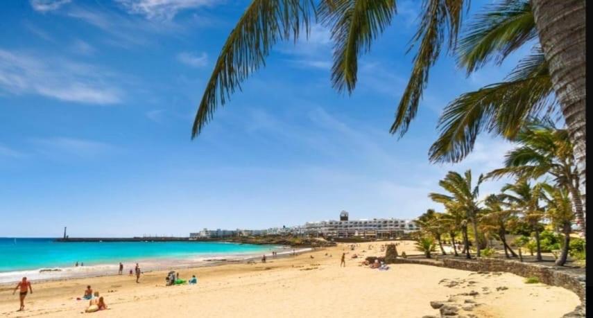 a beach with palm trees and people on the beach at CASA DRAGOS in Costa Teguise