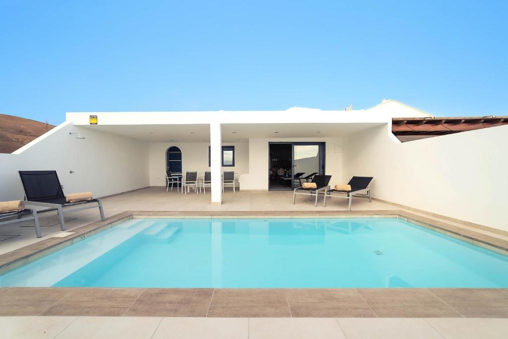 a large swimming pool with chairs and a house at Villa Garoé in Playa Quemada