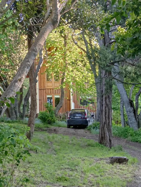 a car parked in front of a house with trees at Casita en el bosque in San Carlos de Bariloche