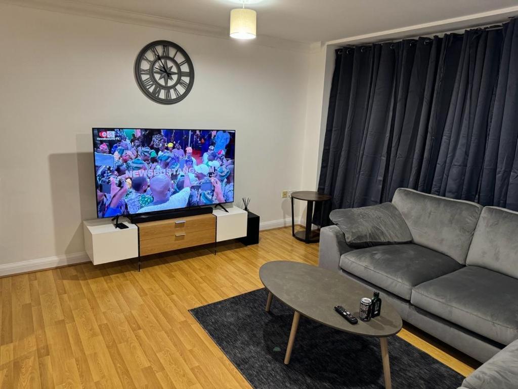a living room with a couch and a flat screen tv at LUXURY APARTMENTS in Dagenham